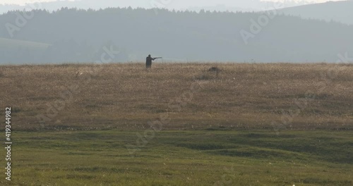 Hunter in camouflage with a gun and dog. Man goes hunting with a gun at sunrise.