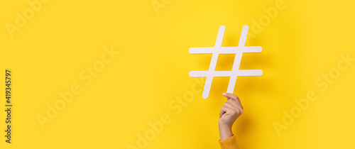 hand showing HASHTAG over yellow background, business concept, panoramic mock-up photo