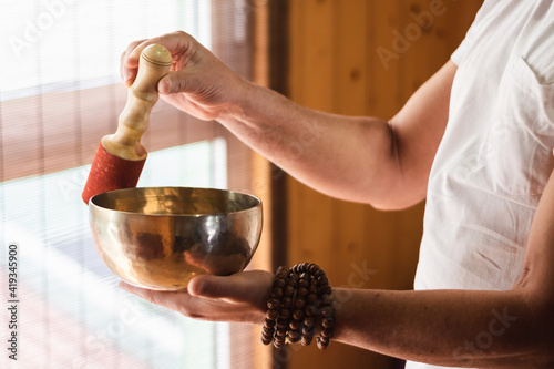 Man with a mala holding and playing a Tibetan bowl