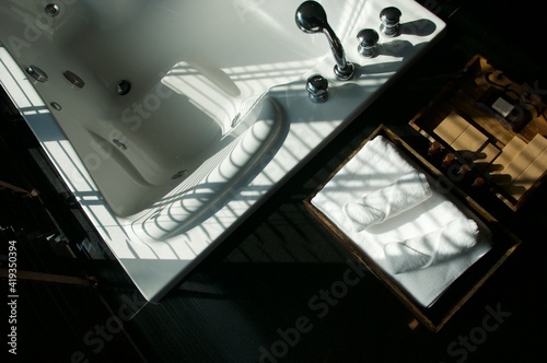 Light and shadow on the granite floor and Warm lighting in spa resort, Close up of spa essentials and towels on wooden tray in bathroom, essential oil. Spa products set conception.