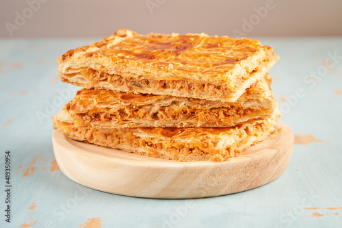 Closeup of stacked portions of an empanada with natural ingredients such a tomato, onion, pepper, tuna, egg and dough of wheat on a wooden plate. Tuna pie. Typical Galician dish from Galicia and Spain