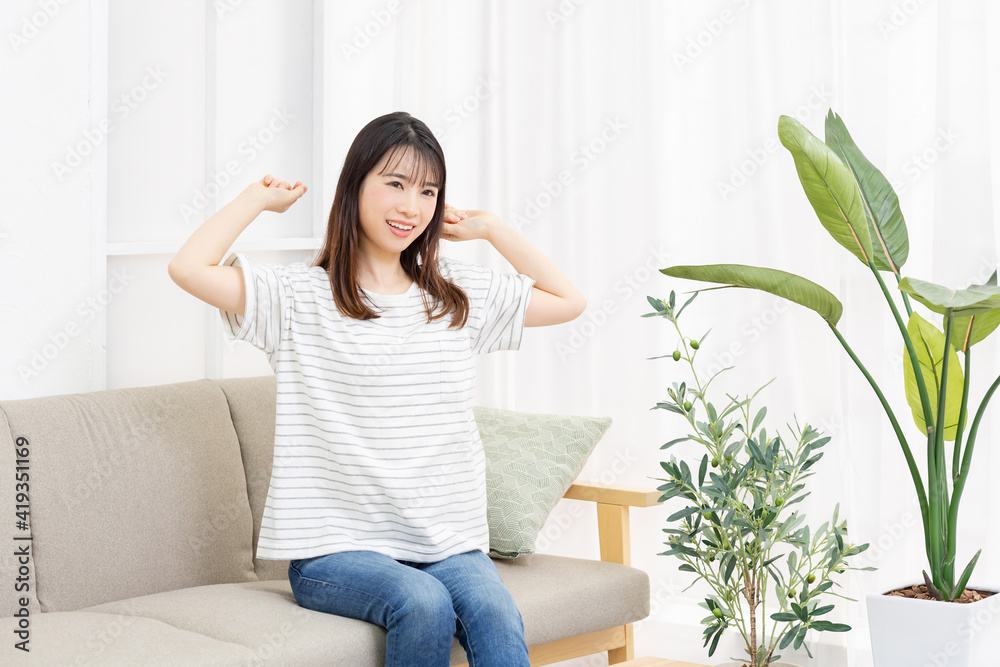 部屋のソファに座って深呼吸をする若い女性 部屋のソファに座って深呼吸をする若い女性