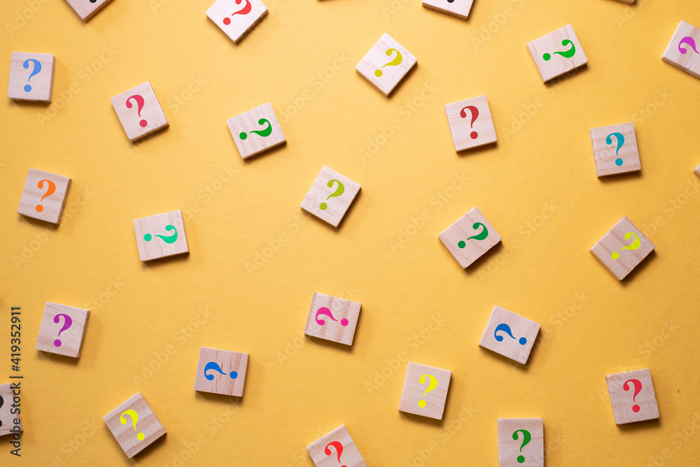 Colorful question mark symbol on wooden tile agains yellow background. Concept of Diversity, FAQ, Q and A and questions