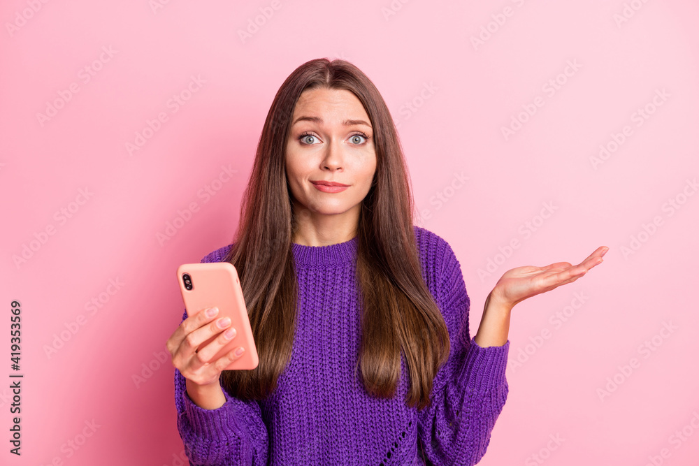 Photo of optimistic girl hold telephone hand empty space wear lilac sweater isolated on pastel pink color background Photo of optimistic girl hold telephone hand empty space wear lilac sweater isolated on pastel pink color background