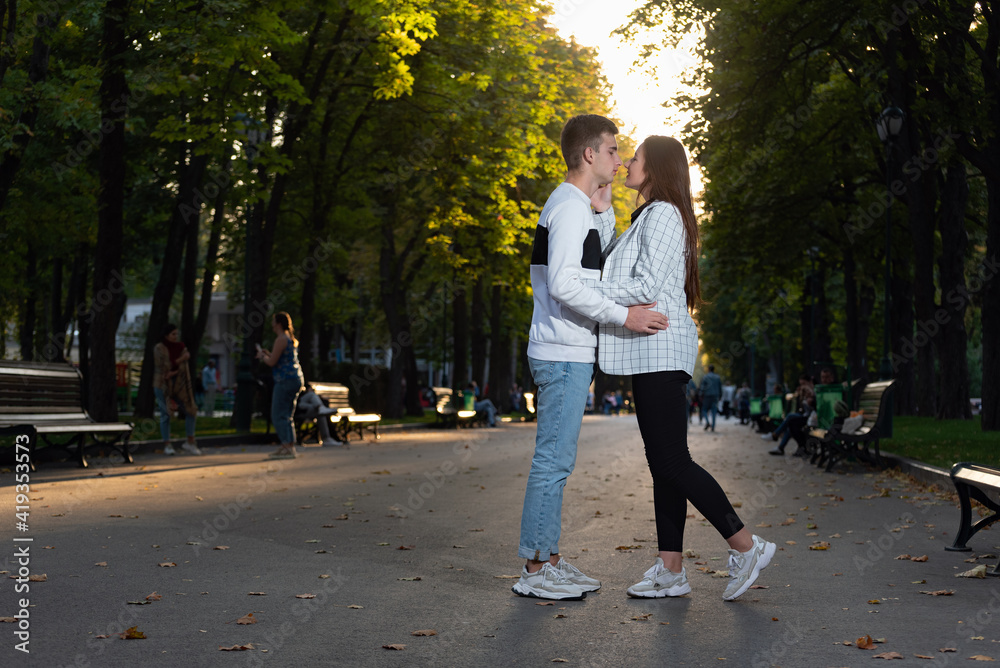 Fototapeta premium Happy young couple kissing in park. Full size portrait. First date