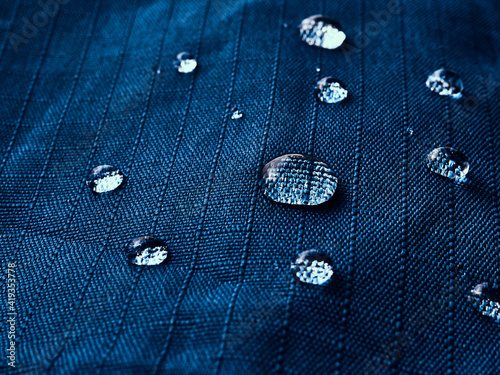 Water drops on waterproof membrane fabric. Detail view of texture of blue waterproof cloth.