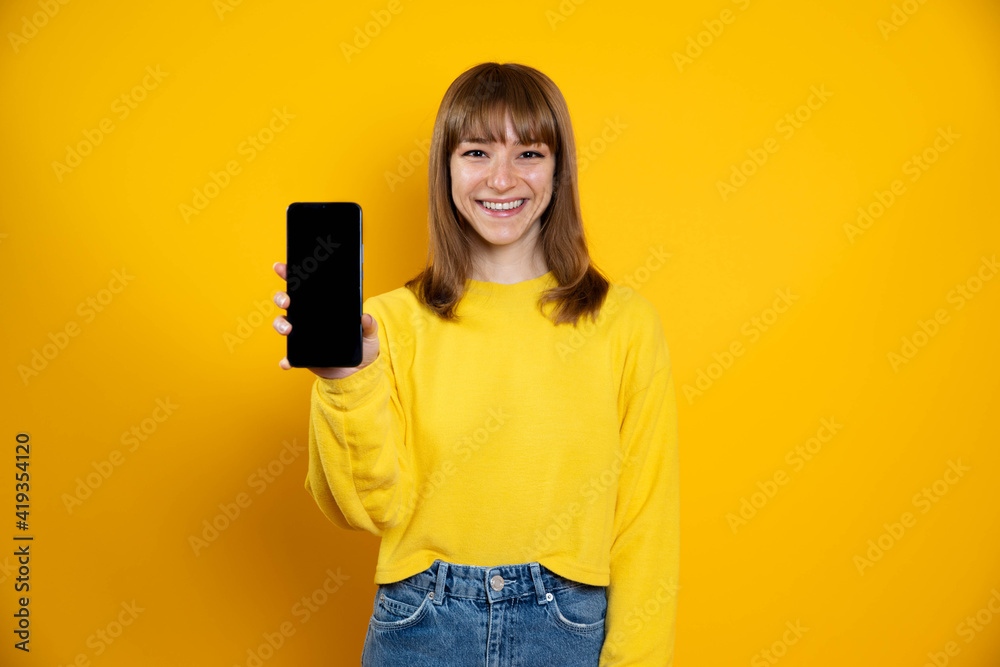 Isolated woman on a yellow background showing showing blank screen mobile phone - Concept about people and technology Isolated woman on a yellow background showing showing blank screen mobile phone - Concept about people and technology