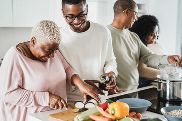 Happy black family cooking inside kitchen at home - Father, daughter, son and mother having fun preparing lunch - People lifestyle concept - Main focus on boy face