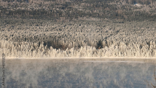 Winter landscape. The river in the fog and the forest in the frost.