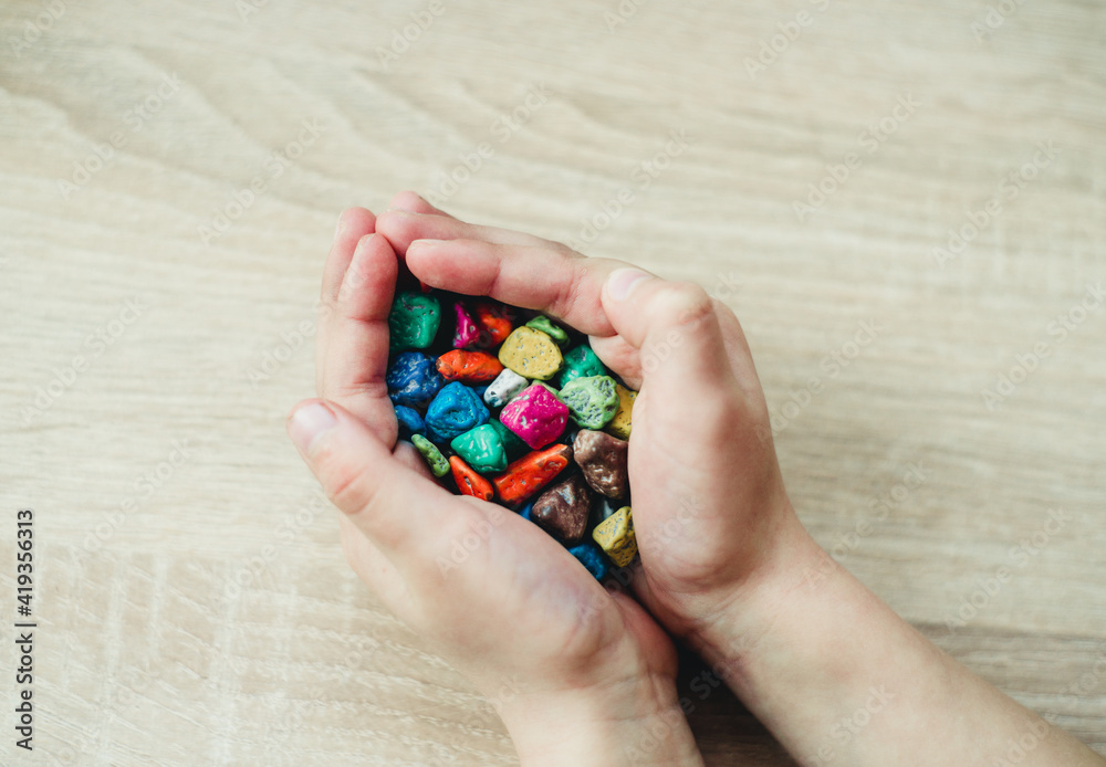 children's hands are holding colorful pebbles children's hands are holding colorful pebbles