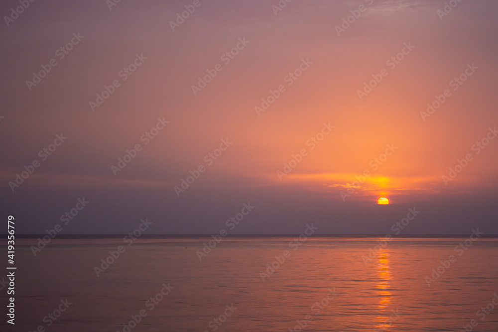 Amazing purple evening sky over Indian ocean. Idyllic sunset over tropical beach. Sunset with sunny path in evening dusk. Tranquil twilight over calm water. Peaceful seascape. Evening sun reflection.
