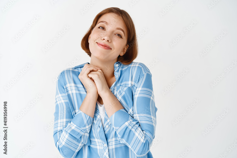 Pretty young girl admire something cute, sighing and clasping hands together, smiling and looking fascinated by something beautiful, white background Pretty young girl admire something cute, sighing and clasping hands together, smiling and looking fascinated by something beautiful, white background