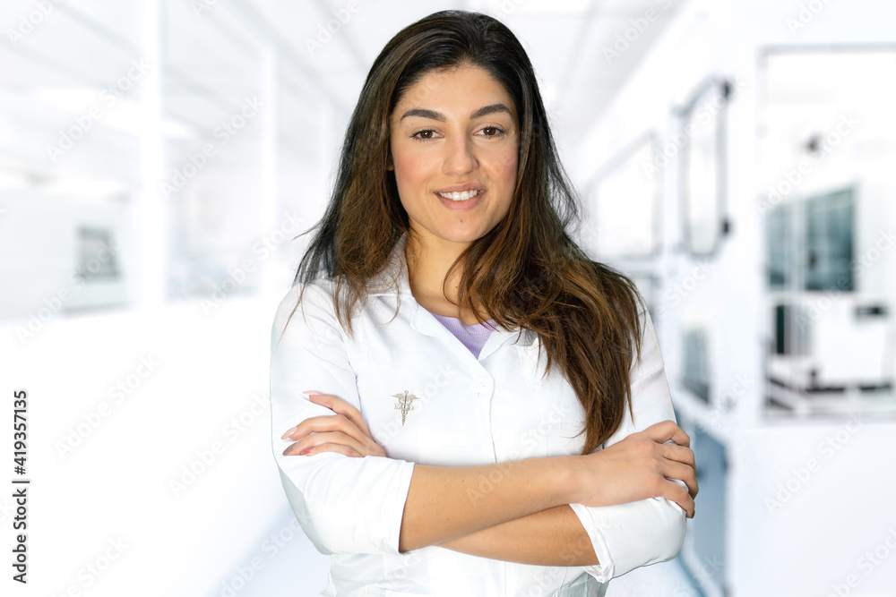 A beautiful smiling female doctor with medical gown and pin on blurred background, perfect shot for professions, research, vaccines, medicine and health. A beautiful smiling female doctor with medical gown and pin on blurred background, perfect shot for professions, research, vaccines, medicine and health.