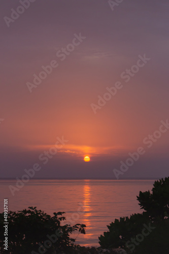 Amazing purple evening sky over Indian ocean. Idyllic sunset over tropical beach with trees silhouettes. Sunset with sunny path in evening dusk. Tranquil twilight over calm water. Peaceful seascape. © Nataliia