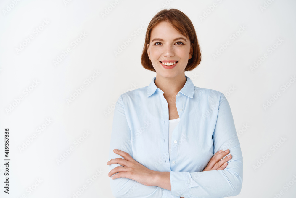 Portrait of confident young female professional looking determined. Woman in office blouse cross arms on chest, smiling motivated, standing on white background Portrait of confident young female professional looking determined. Woman in office blouse cross arms on chest, smiling motivated, standing on white background