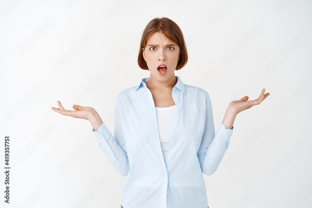 Whats problem. Confused and shocked young woman cant understand why, raising hands up and open mouth frustrated, standing on white background Whats problem. Confused and shocked young woman cant understand why, raising hands up and open mouth frustrated, standing on white background