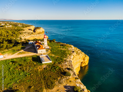 Cliffy coast with Alfazinha Lighthouse in Carvoeiro, Algarve, Portugal photo