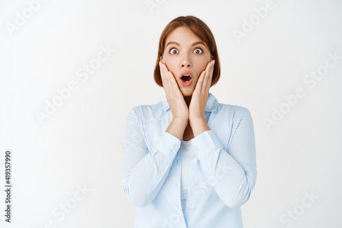 Portrait of surprised businesswoman gasping and staring with disbelief at camera, saying wow amazed, checking out awesome advertisement, white background