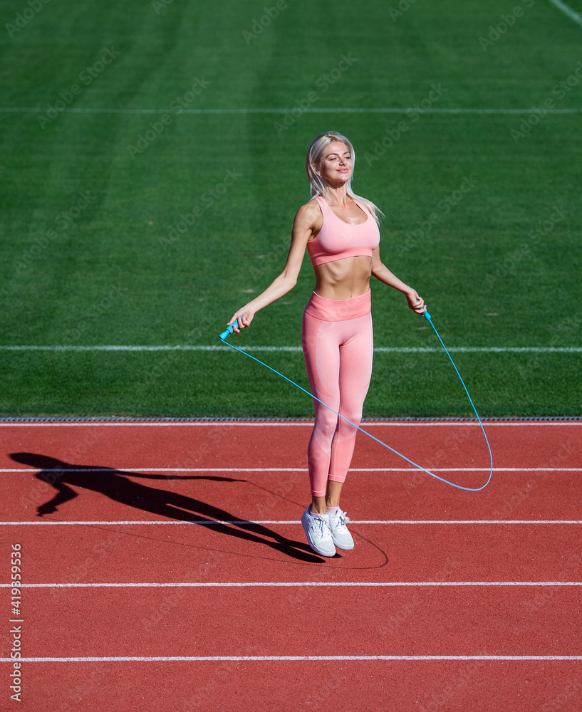 sexy fitness woman in sportswear. athletic lady use jumping-rope on stadium. female athlete do jumping sport workout. trainer or coach training with skipping rope. healthy and sporty