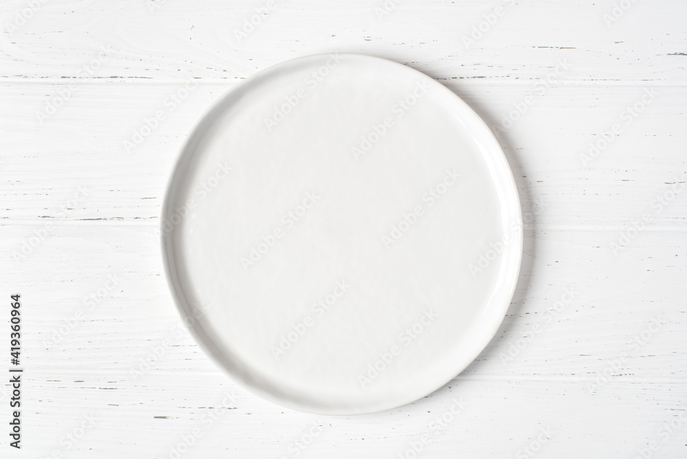 An empty plate on a white wooden table. Top view. An empty plate on a white wooden table. Top view.