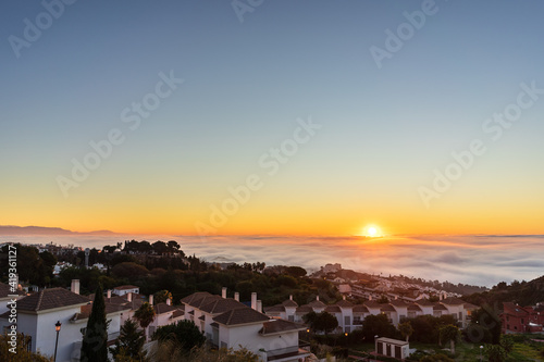 Fotografie Sol emergiendo sobre mar de nubes e iluminando Benalmádena Pueblo, amanecer