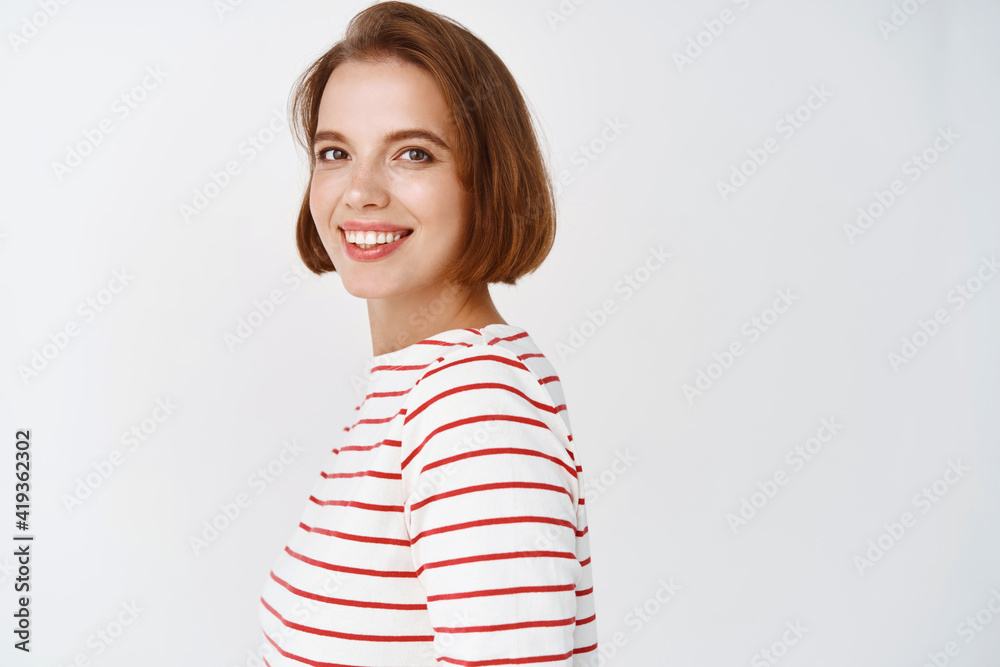 Beauty. Portrait of confident attractive woman turn head at camera, smiling and looking happy, standing against white background Beauty. Portrait of confident attractive woman turn head at camera, smiling and looking happy, standing against white background
