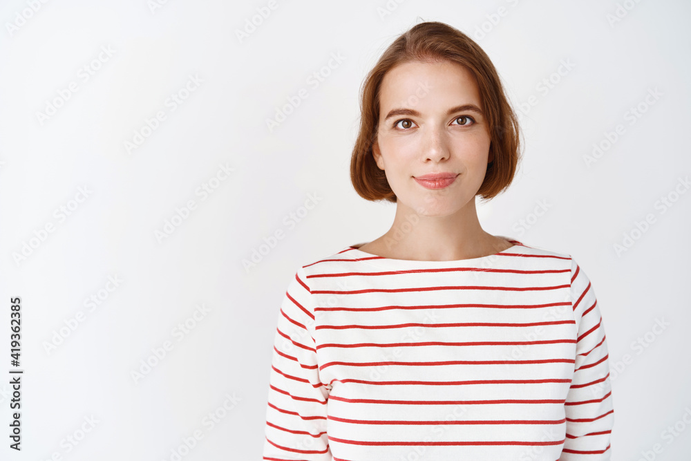 Beauty. Portrait of young confident woman with natural light facial skin, smile tenderly at camera, standing in striped blouse against white background Beauty. Portrait of young confident woman with natural light facial skin, smile tenderly at camera, standing in striped blouse against white background