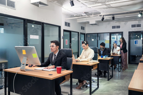Group of young asian colleagues working with laptop at desk in modern office. Female manager consulting with employee