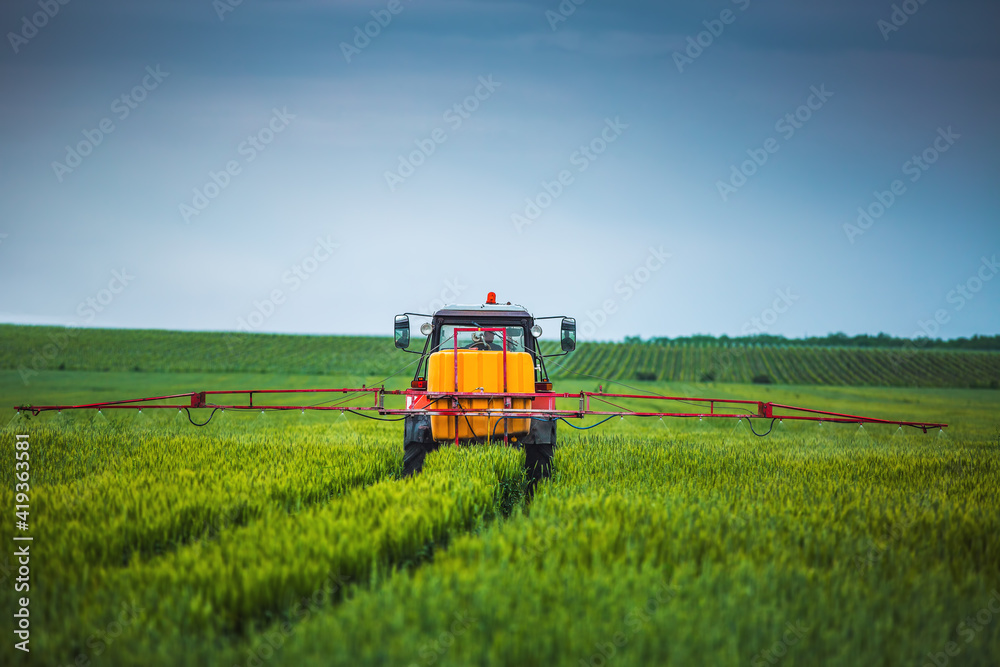 Fototapeta premium Farming tractor plowing and spraying on field