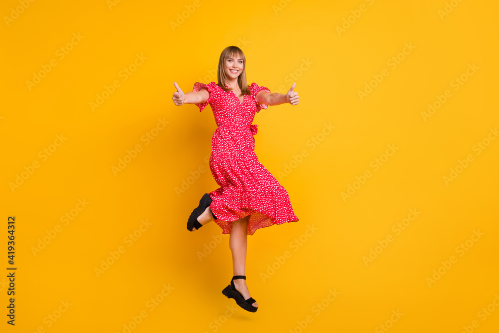 Full body photo of blond haired cheerful woman show thumbs up approve jump up isolated on yellow color background