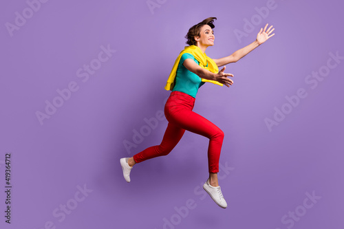 Full length photo of lady jump arms empty space wear knotted pullover t-shirt pants footwear isolated violet color background © deagreez