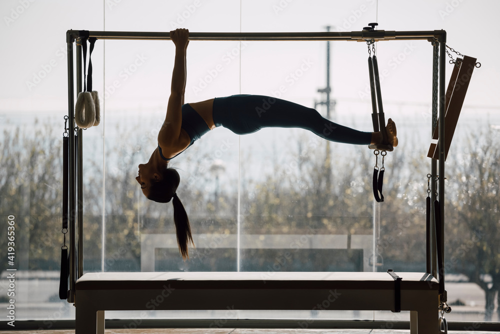Foto de Fit female coach hanging hands and feet from the Pilates