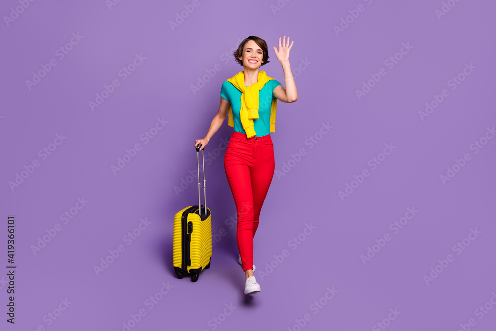 Full length photo of lady go with case wave hand wear tied sweater t-shirt pants sneakers isolated violet color background Full length photo of lady go with case wave hand wear tied sweater t-shirt pants sneakers isolated violet color background