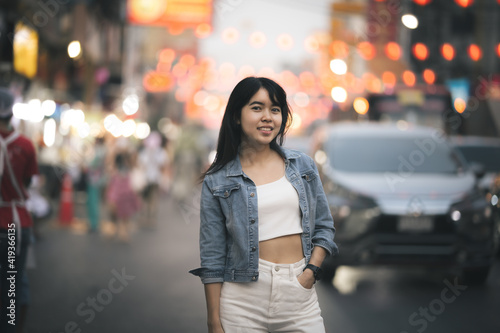 Beautiful Asian woman who has long hair travels to the festival at Yaowarat Chinatown in Thailand. Street photography of traveler woman at night. © amornchaijj