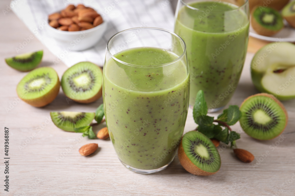 Delicious kiwi smoothie and ingredients on white wooden table Delicious kiwi smoothie and ingredients on white wooden table