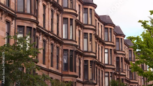 Pan: Large Sandstone Tenements With Enormous Windows Above Lush Green Trees photo