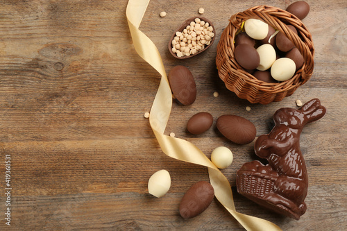 Chocolate Easter bunny and eggs on wooden table, flat lay. Space for text