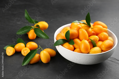 Fresh ripe kumquats in bowl on black table