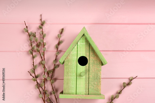Beautiful green bird house and willow branches on pink wooden background. Spring flat lay composition © New Africa