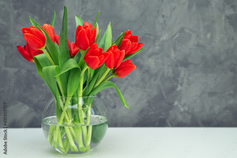 Bouquet of red tulips in a vase on a gray background. Bouquet of red tulips in a vase on a gray background.