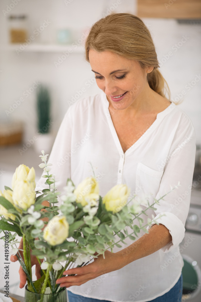 Pretty housewife putting flowers into the vase Pretty housewife putting flowers into the vase