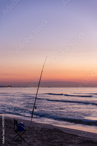 Fishing rod with sunrise and beautiful colors at malvarosa beach of the City of valencia, costa blanca, spain