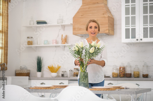 Pretty housewife putting beautiful flowers into the vase