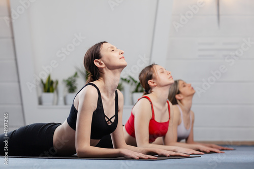 Three girls practicing yoga. Yoga instructor with her students meditating in a studio.