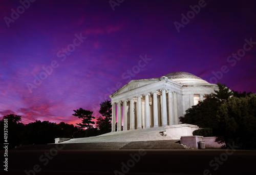 The white marble of the Jefferson Memorial stands out against the dark pink and purple twilight morning sky in Washington DC.
