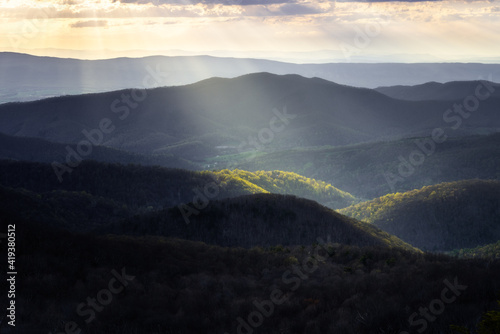 A spotlight of sunlight illuminates the Spring greens down in a valley of Shenandoah National Park. © Nick