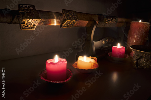 Shaolin sword lit by candlelight in a dark room