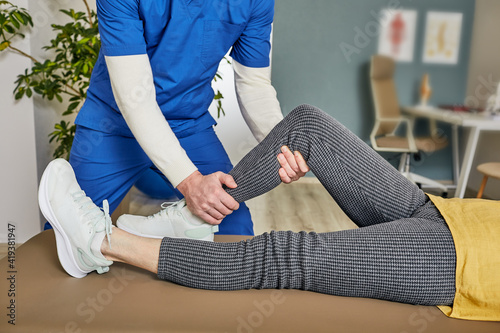 Physiotherapist helping elderly woman do leg workout exercises after knee injury