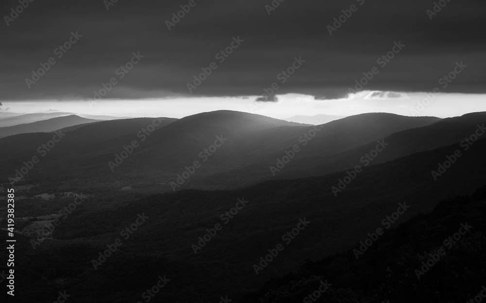 Morning light spilling over a ridge line of Shenandoah National Park under a dark cloud deck. Shot in black & white.