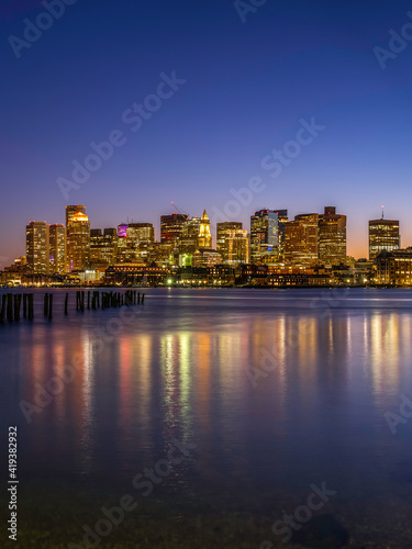 Boston Nightscape Skyline and Weathered Pier with Damaged Pilings. Harmony of Nature  Civilization  and Reflections of Lights and Time.